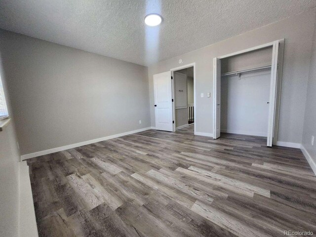 25 Castle Royal Dr, Pueblo, CO 81005 - unfurnished bedroom with wood finished floors, a textured ceiling, a closet, and baseboards