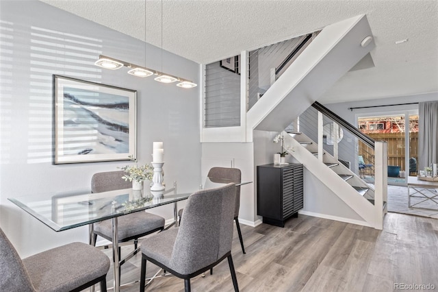 dining space featuring stairs, a textured ceiling, vaulted ceiling, and wood finished floors