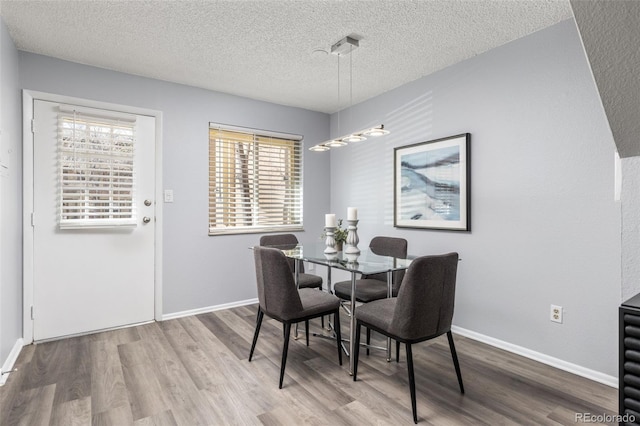 dining room featuring a textured ceiling, baseboards, and wood finished floors