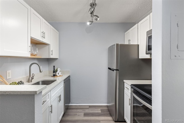 kitchen featuring white cabinets, a textured ceiling, stainless steel appliances, and a sink