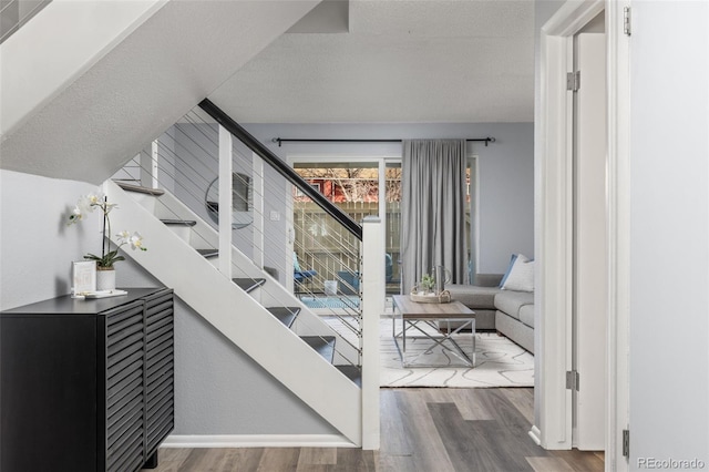 staircase with a textured ceiling and wood finished floors