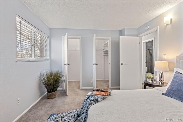 bedroom featuring a textured ceiling, a spacious closet, baseboards, and light colored carpet