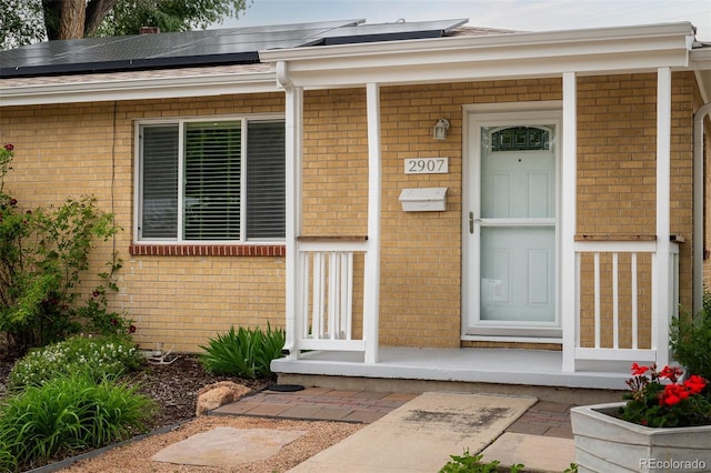 2907 Pennsylvania Ave, Colorado Springs, CO 80907 - doorway to property with brick siding, solar panels, and covered porch