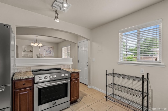 2907 Pennsylvania Ave, Colorado Springs, CO 80907 - kitchen featuring appliances with stainless steel finishes, light countertops, arched walkways, light tile patterned floors, and a chandelier