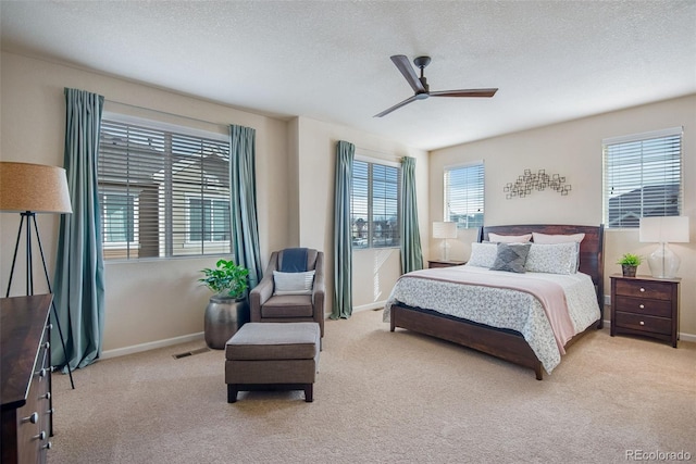 carpeted bedroom with a textured ceiling, visible vents, baseboards, and a ceiling fan