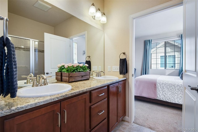 ensuite bathroom with a shower stall, tile patterned floors, double vanity, and a sink