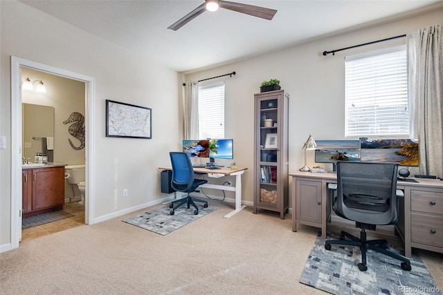 office space with light carpet, baseboards, and a ceiling fan