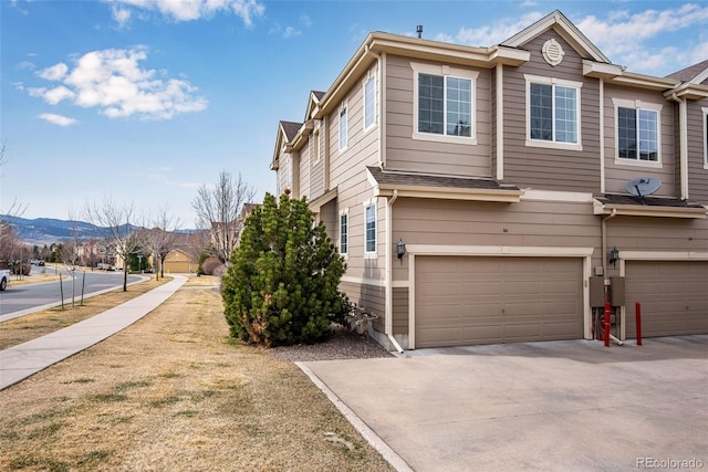 view of property exterior featuring concrete driveway, a mountain view, and an attached garage