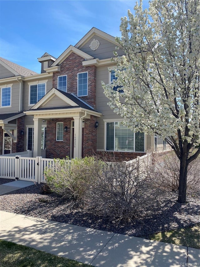 view of front of house featuring a fenced front yard, a gate, and brick siding