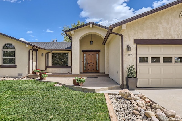view of exterior entry featuring roof with shingles, an attached garage, stucco siding, and a lawn