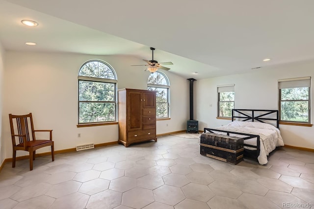 bedroom featuring visible vents, baseboards, a wood stove, lofted ceiling, and recessed lighting
