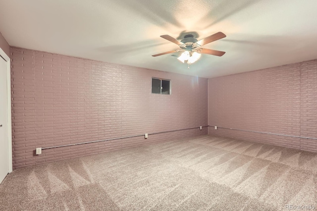 unfurnished room featuring brick wall, ceiling fan, and carpet