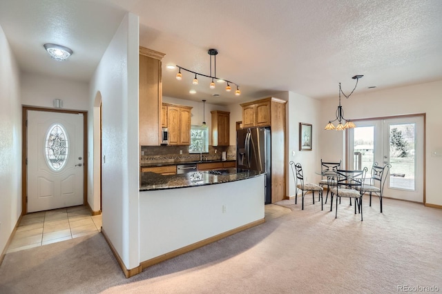 kitchen with a peninsula, stainless steel appliances, a textured ceiling, baseboards, and light carpet