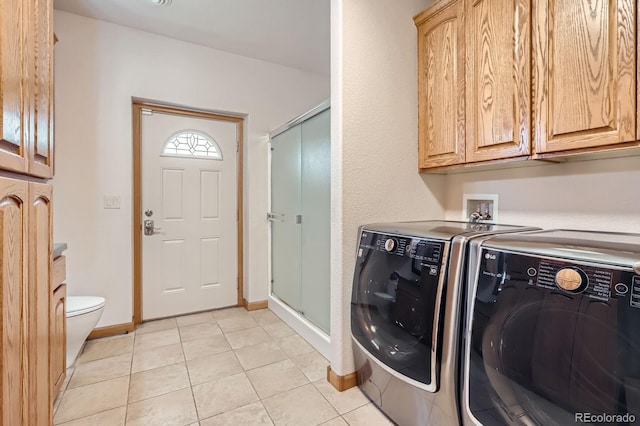 laundry area featuring cabinet space, washer and clothes dryer, baseboards, and light tile patterned floors