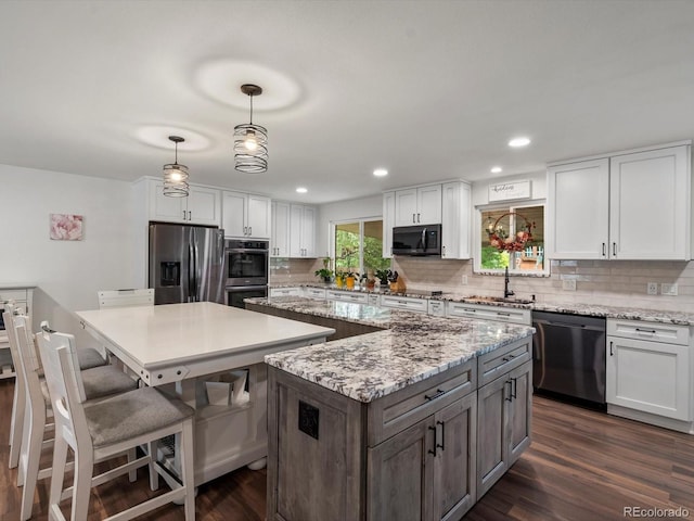 6166 S Dover St, Littleton, CO 80123 - kitchen with stainless steel appliances, a center island, white cabinets, decorative backsplash, and recessed lighting