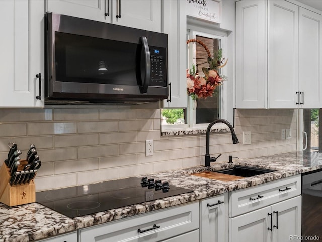 6166 S Dover St, Littleton, CO 80123 - kitchen with black electric cooktop, dishwasher, white cabinets, and decorative backsplash