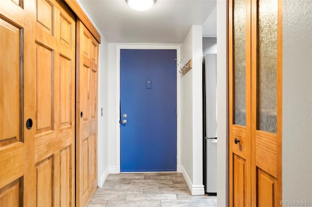 hall with baseboards and light wood finished floors