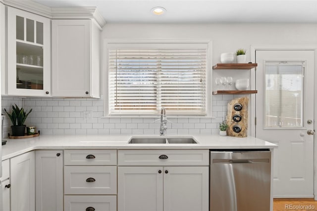 kitchen featuring tasteful backsplash, dishwasher, sink, white cabinets, and light hardwood / wood-style flooring