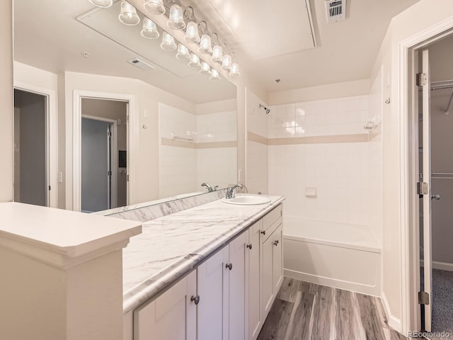 bathroom with hardwood / wood-style floors, tiled shower / bath combo, and vanity