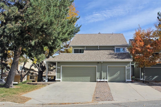 traditional-style home featuring concrete driveway, roof with shingles, and a garage