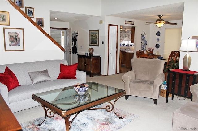 carpeted living room featuring ceiling fan, a textured ceiling, and sink