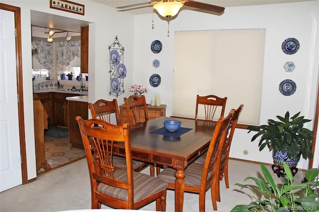 dining space with sink, light colored carpet, and ceiling fan