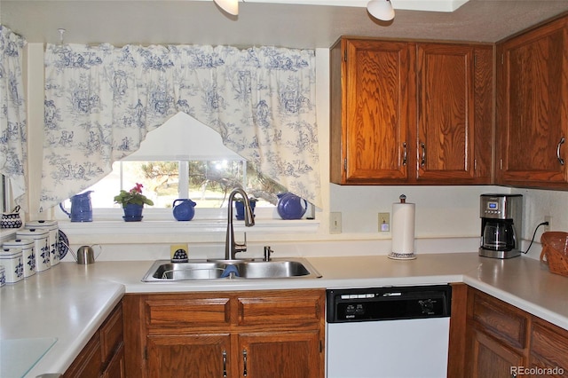 kitchen with white dishwasher, light countertops, a sink, and brown cabinets