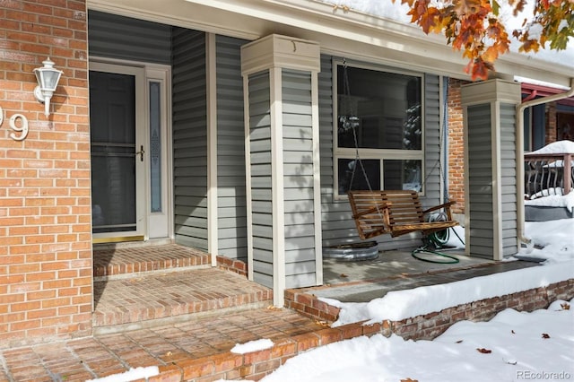 snow covered property entrance with a porch