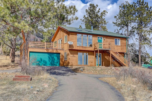 chalet / cabin featuring stairway, a garage, and driveway