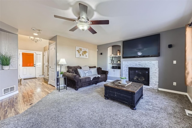 9990 Jasper St, Commerce City, CO 80022 - carpeted living area with a ceiling fan, built in shelves, baseboards, a glass covered fireplace, and a chandelier