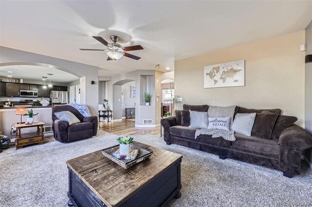 9990 Jasper St, Commerce City, CO 80022 - living area featuring arched walkways, ceiling fan, light colored carpet, and baseboards