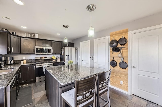9990 Jasper St, Commerce City, CO 80022 - kitchen with appliances with stainless steel finishes, a kitchen bar, dark brown cabinets, dark stone countertops, and decorative light fixtures