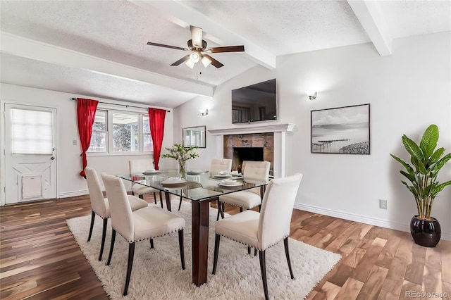 3762 S Fenton Way, Denver, CO 80235 - dining room with ceiling fan, baseboards, wood finished floors, a tiled fireplace, and a textured ceiling