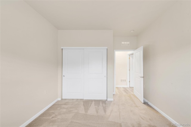 unfurnished bedroom with light colored carpet and a closet