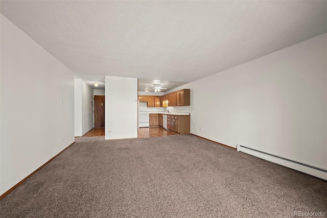 unfurnished living room featuring light carpet, sink, a baseboard radiator, and a textured ceiling