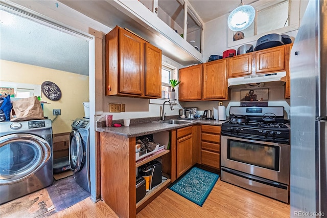939 Conejos St, Colorado Springs, CO 80903 - kitchen with appliances with stainless steel finishes, under cabinet range hood, separate washer and dryer, brown cabinetry, and light wood-style floors