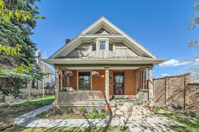 victorian house featuring covered porch and brick siding