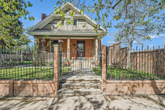 3777 Newton St, Denver, CO 80211 - view of front facade with a porch, a fenced front yard, a chimney, a gate, and brick siding