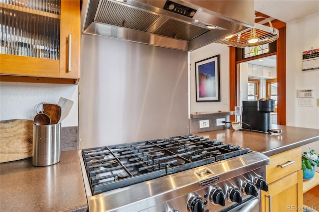 kitchen with wall chimney exhaust hood, stove, and dark countertops
