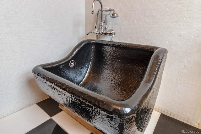 bathroom view of tile walls, a freestanding bath, and a sink