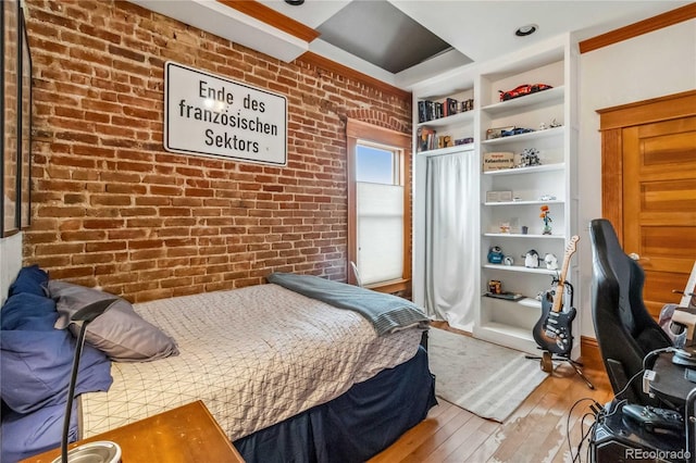 bedroom with hardwood / wood-style flooring and brick wall