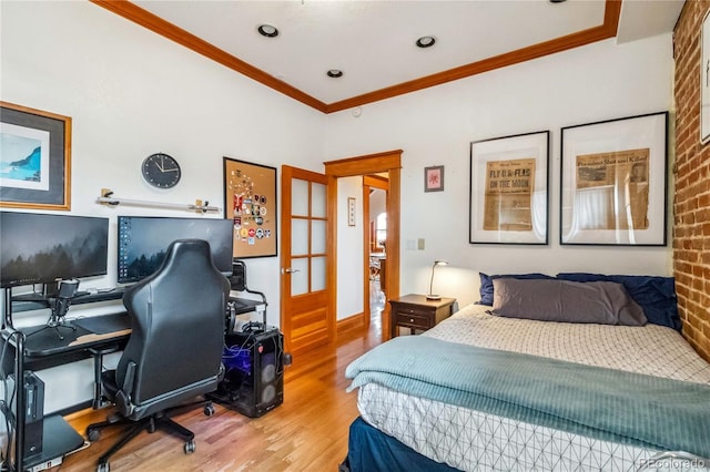 bedroom with wood finished floors, crown molding, an office area, and french doors