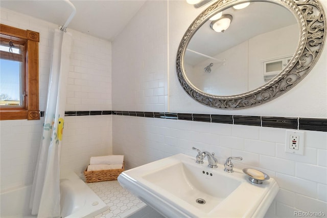 full bathroom with a sink, tile walls, and shower / bath combo with shower curtain