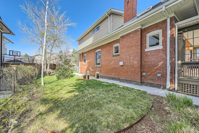 back of house featuring a chimney, a yard, and brick siding