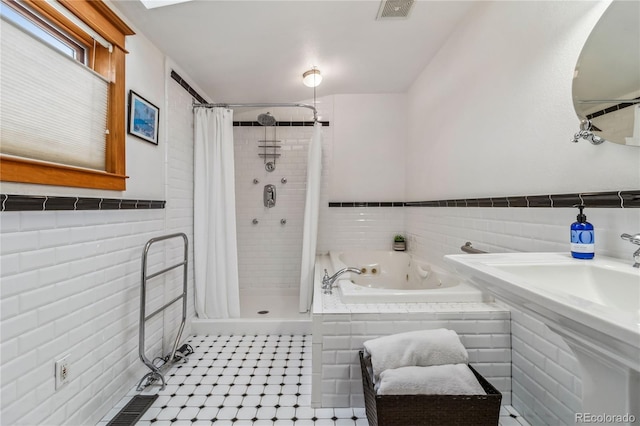 bathroom featuring tile walls, a jetted tub, a stall shower, tile patterned flooring, and wainscoting