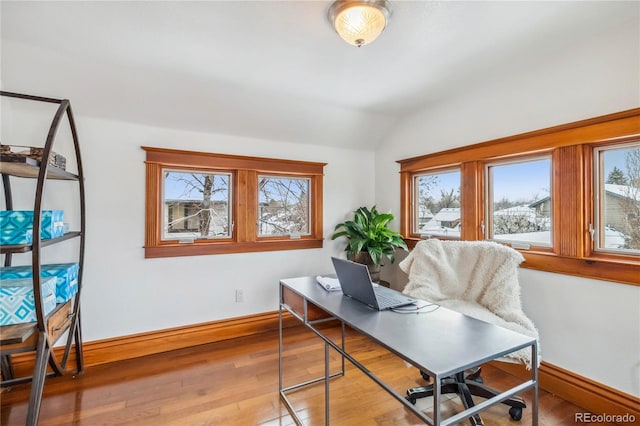 home office featuring healthy amount of natural light, vaulted ceiling, hardwood / wood-style floors, and baseboards