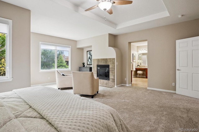 2601 Pemberly Ave, Highlands Ranch, CO 80126 - bedroom with light colored carpet, a tiled fireplace, baseboards, a raised ceiling, and connected bathroom