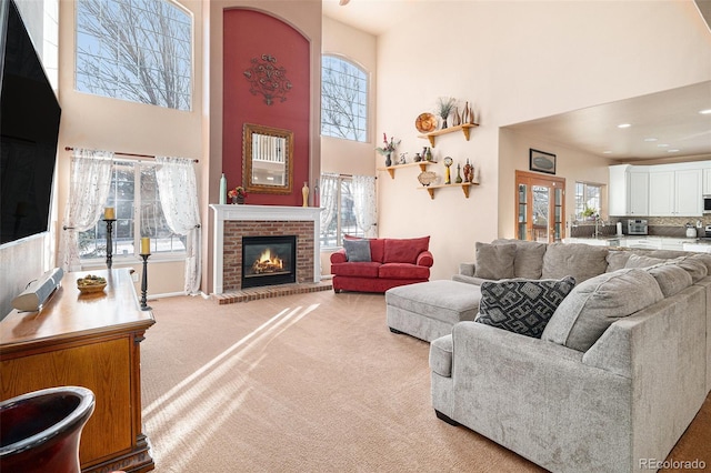 living room with a high ceiling, a fireplace, carpet floors, and a wealth of natural light