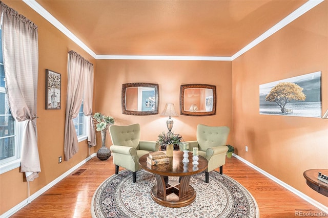 sitting room with wood-type flooring and ornamental molding