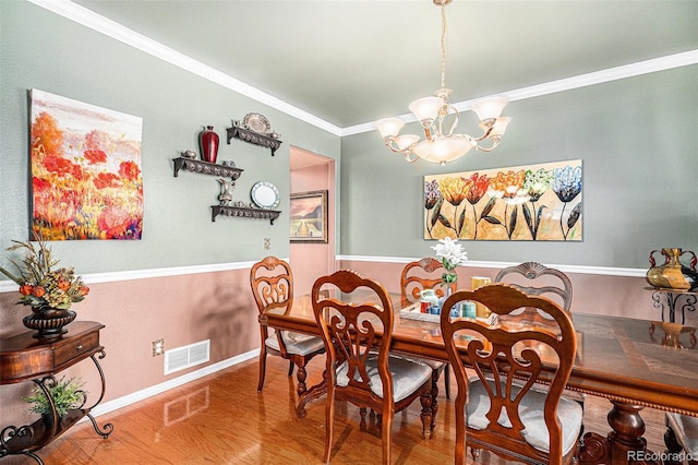 dining area featuring ornamental molding, hardwood / wood-style floors, and a chandelier